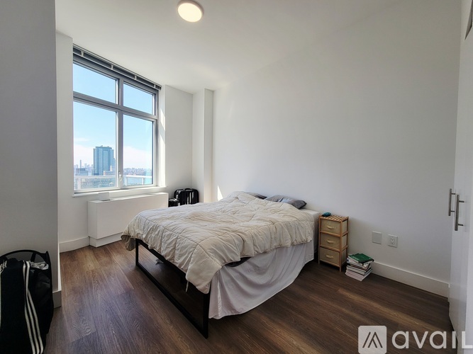 A bedroom with a large bed and a window overlooking a cityscape.