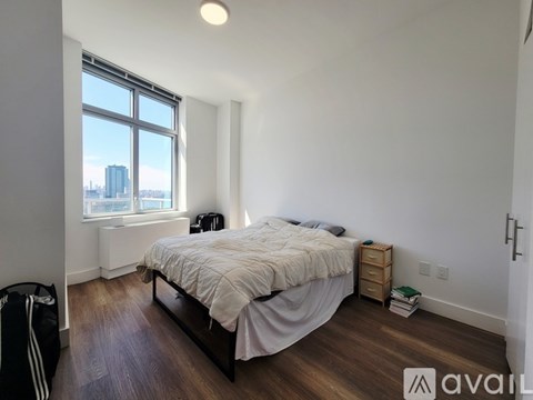 A bedroom with a large bed and a window overlooking a cityscape.