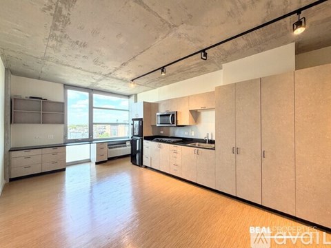 A spacious kitchen with wooden floors and white cabinets is available for rent.