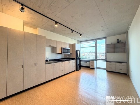 A spacious kitchen with wooden floors and white walls.