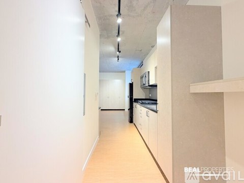 A long, narrow hallway with a kitchen area at the end.