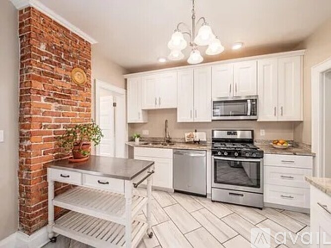 A kitchen with white cabinets and a brick wall.