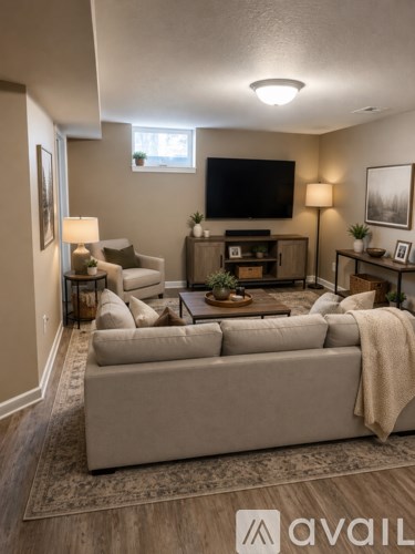 A living room with a large couch and a flat screen TV mounted on the wall.