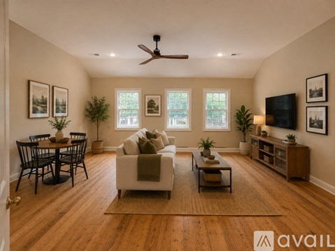 A living room with a couch, a dining table, and a ceiling fan.