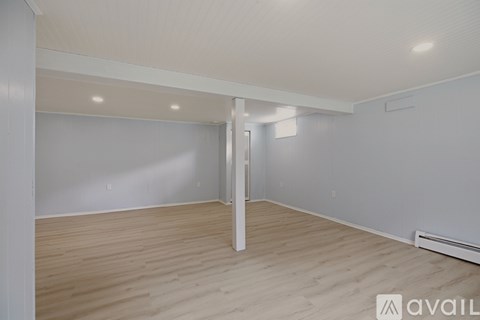 A spacious room with wooden flooring and white walls.