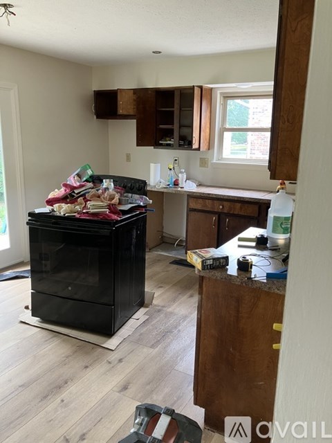A black stove in a kitchen with wooden cabinets and a window.