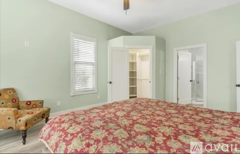 A bedroom with a floral bedspread and a patterned chair.