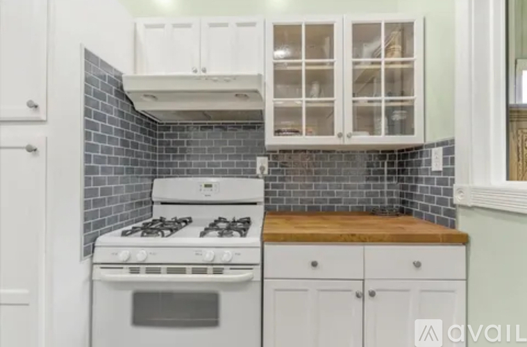 A kitchen with a white stove and cabinets.