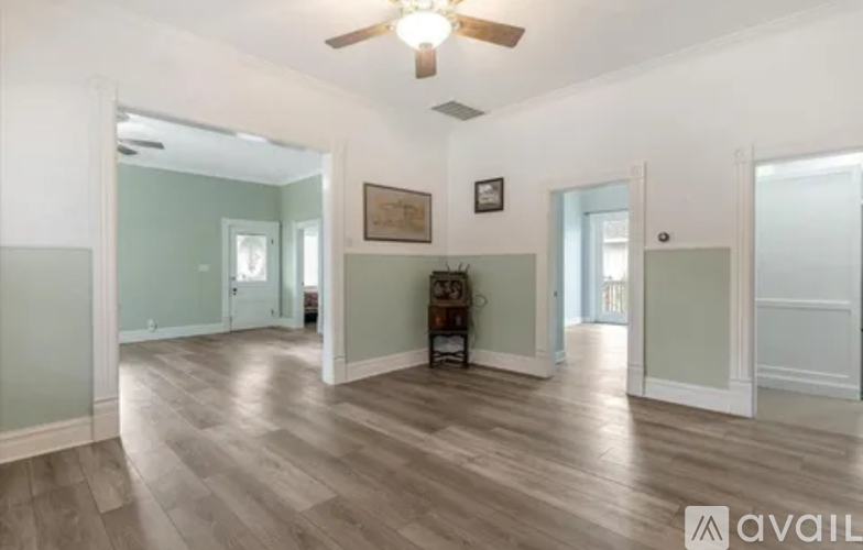 A spacious room with wood flooring and a ceiling fan.