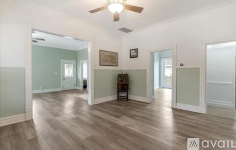 A spacious room with wood flooring and a ceiling fan.