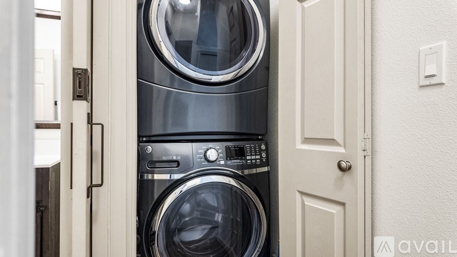 A washing machine is installed in a small space between a door and a wall.