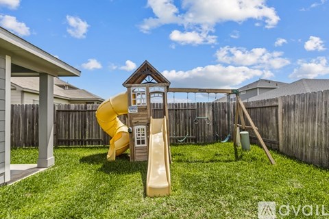 A playground with a yellow slide and a wooden structure.