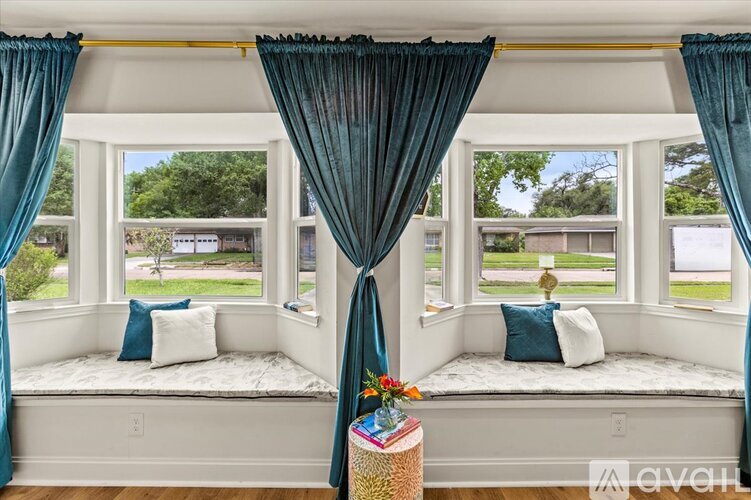 A window seat with a view of a green lawn and trees.