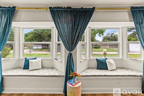 A window seat with a view of a green lawn and trees.