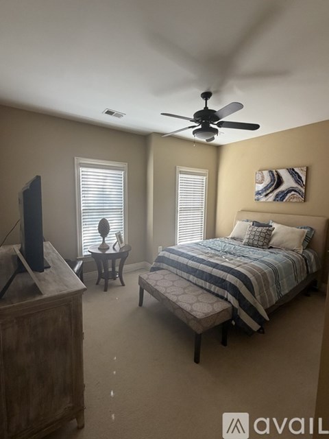 A bedroom with a bed, a dresser, and a ceiling fan.