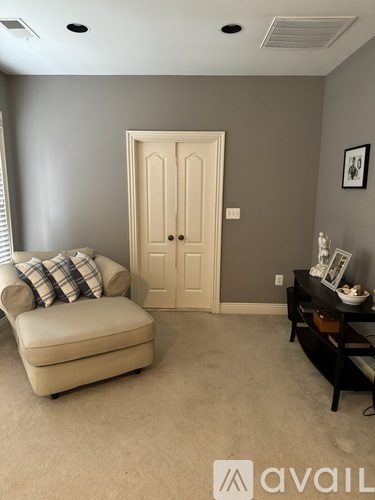 A living room with a beige sofa, a wooden door, and a black coffee table.