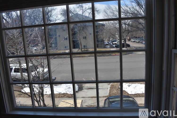A view from a window looking out at a parking lot and a building.