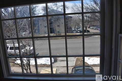 A view from a window looking out at a parking lot and a building.