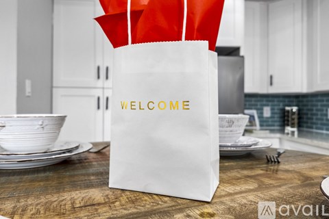 A white paper bag with the word "WELCOME" on it is placed on a wooden table in a kitchen setting.