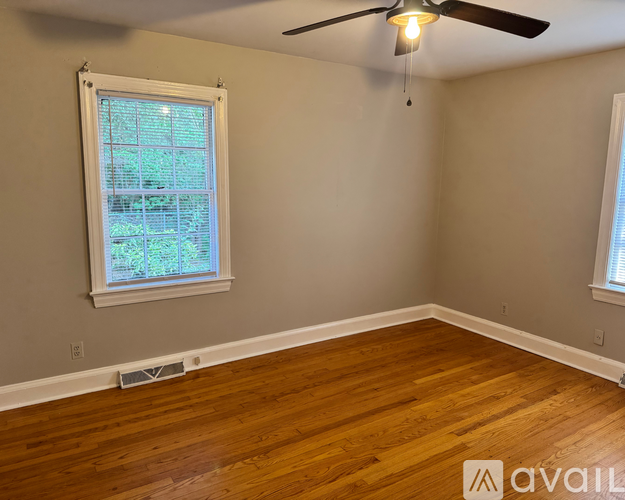 A room with a ceiling fan and a window with a view of trees.