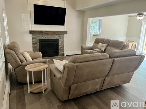 A living room with a grey couch, a chair, and a television mounted above a fireplace.