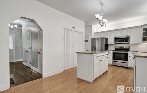 A kitchen with white cabinets and a wooden floor.