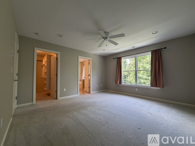 A spacious room with a ceiling fan and carpeted floor.