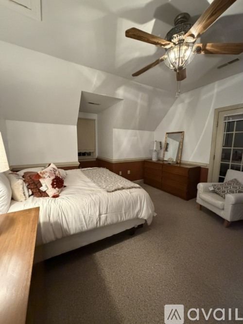 A bedroom with a bed, a chair, and a ceiling fan.