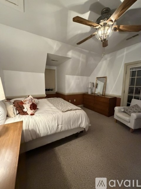 A bedroom with a bed, a chair, and a ceiling fan.