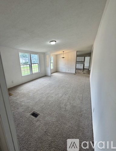 A spacious empty room with a carpeted floor and a window.