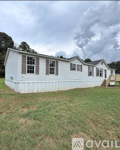 A mobile home with a white exterior and a brown roof.