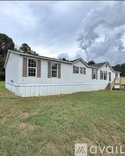 A mobile home with a white exterior and a brown roof.