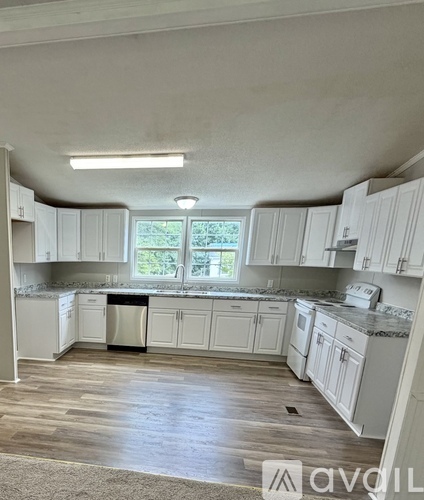 A kitchen with white cabinets and a window.
