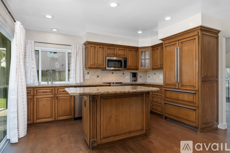 A kitchen with wooden cabinets and a marble countertop.
