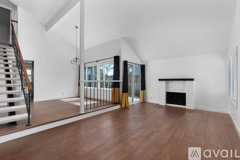 A spacious living room with a fireplace and a staircase.