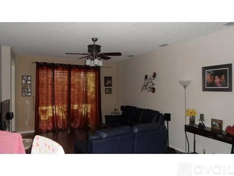 A living room with a blue couch and a ceiling fan.
