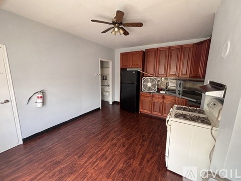 A kitchen with wooden floors and a ceiling fan.