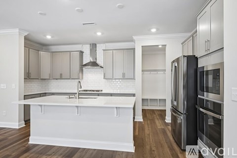 A kitchen with a white island and stainless steel appliances.