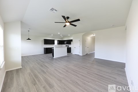 A spacious room with a ceiling fan and a long wooden floor.