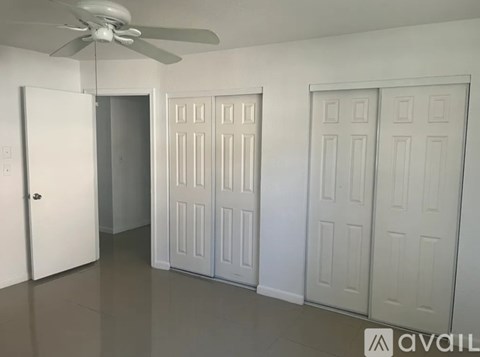 A room with a ceiling fan and three doors.
