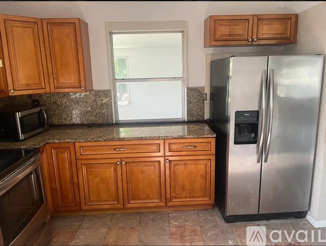 A kitchen with wooden cabinets and a stainless steel refrigerator.