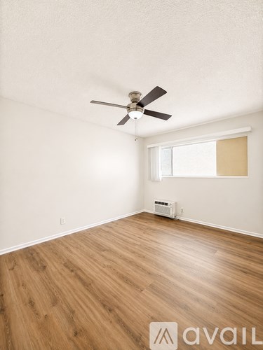 A room with a ceiling fan and wooden flooring.