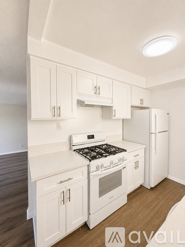 A kitchen with white cabinets and a stove top oven.