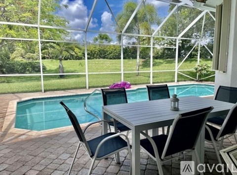 A table with chairs is set up outside with a pool in the background.