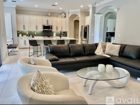 A modern living room with a black leather couch and a glass coffee table.