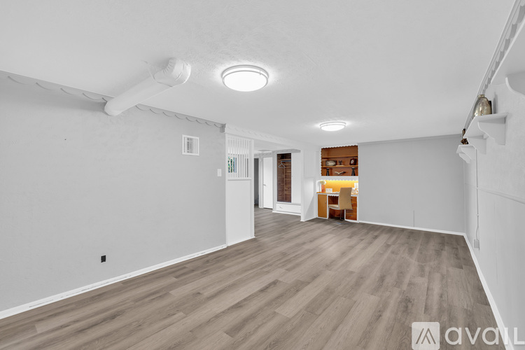 A spacious room with wooden flooring and white walls.