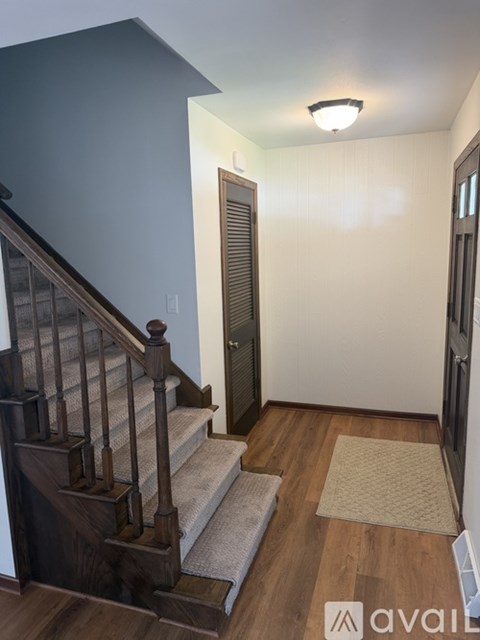 A hallway with a staircase and a door.