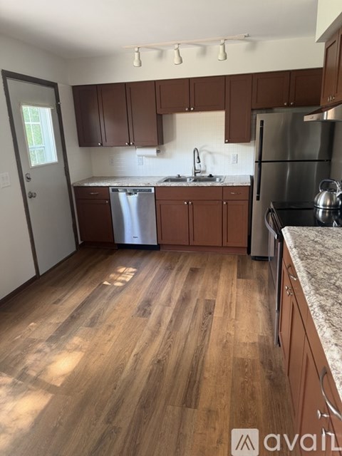 A kitchen with wooden floors and brown cabinets.
