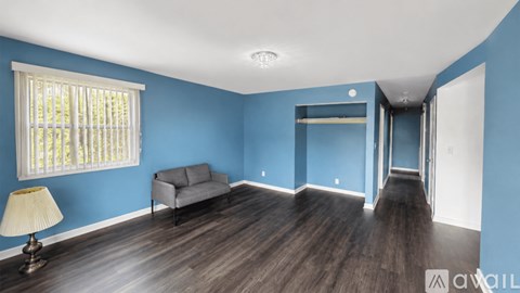 A living room with a grey couch and a lamp on a table.