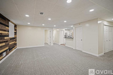 A spacious room with a carpeted floor and a wooden accent wall.